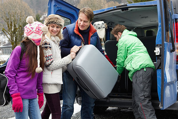 Family removing suitcases from vehicle