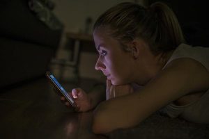 Portrait of a young woman lying on carpet with mobile phone