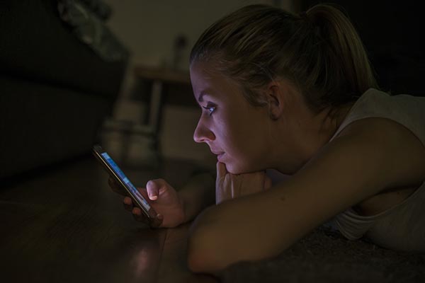 Portrait of a young woman lying on carpet with mobile phone