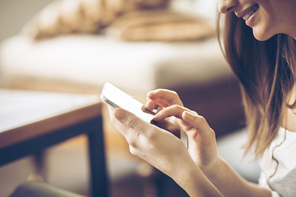 Happy woman typing on smart phone