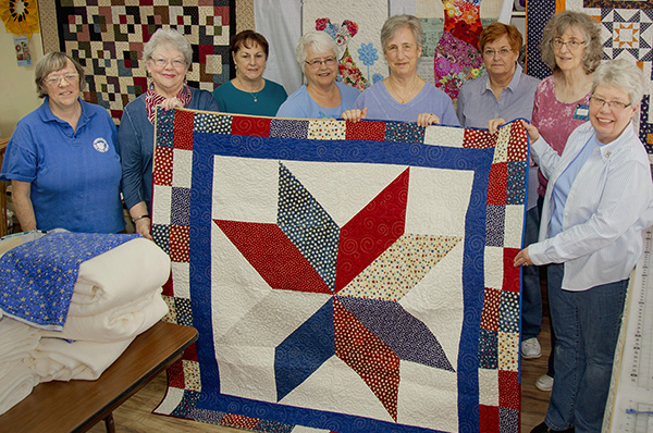 Volunteers of Little Traverse Bay Quilters Guild show Quilt of Valor made for a veteran