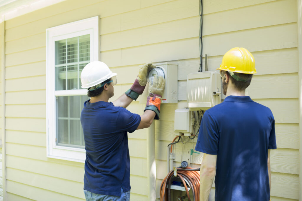 Electrical repair man working on outside meter of home.