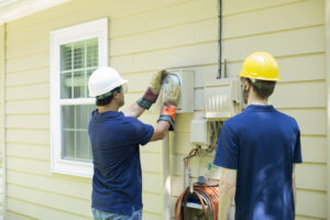 Electrical repair man working on outside meter of home.
