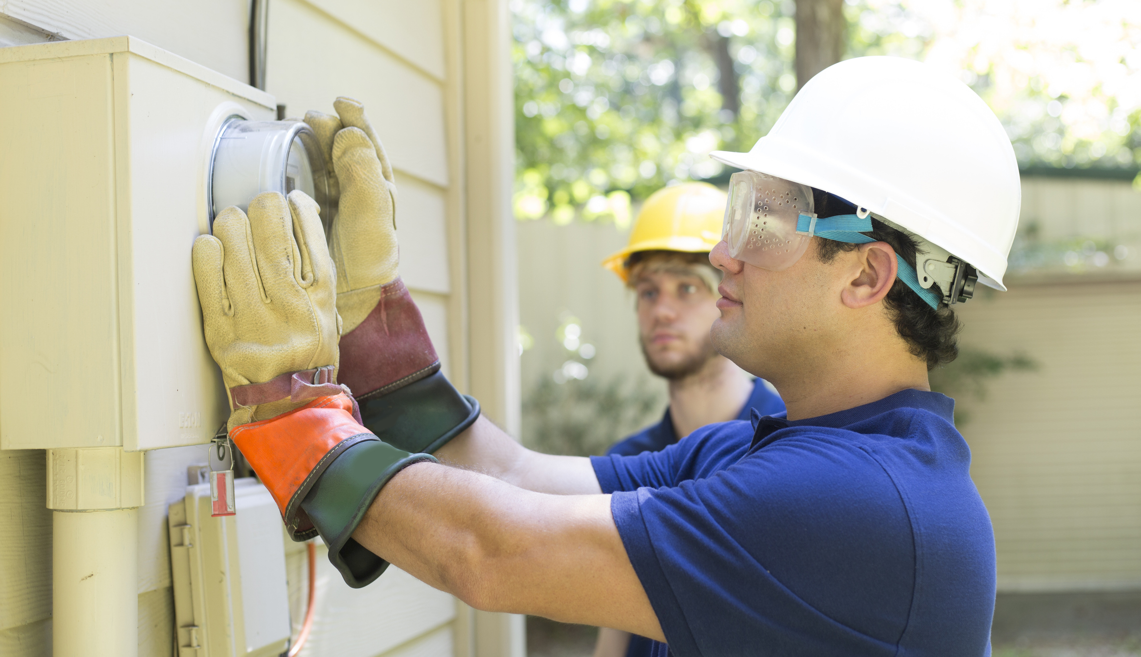 Electrical repair man working on outside meter of home.