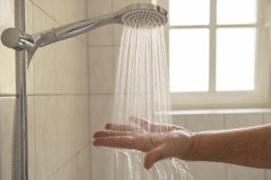 Hand under running shower head.