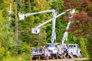Two GLE bucket trucks extended with lineworkers working on poles.