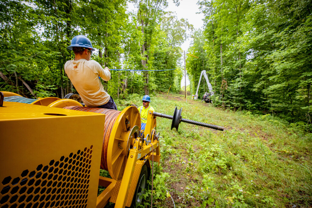 Lineworkers setting an electric pole in the ground.