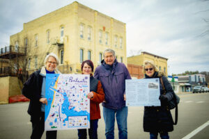 Four members of the Pentwater Historical Society holding up information on the area.