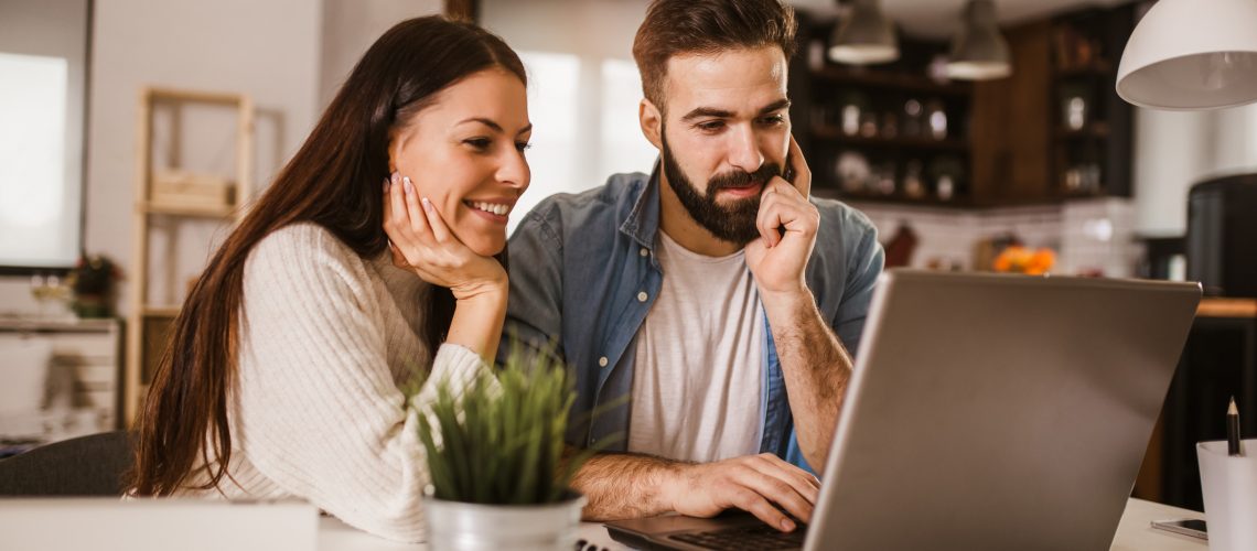 Happy couple enjoying work from home. Happy couple doing business together working at home on the laptop.