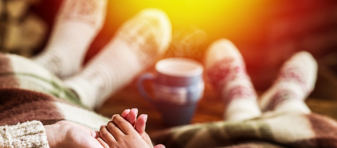 Warming and relaxing near fireplace. Mother and daughter holding hands in front of fire.