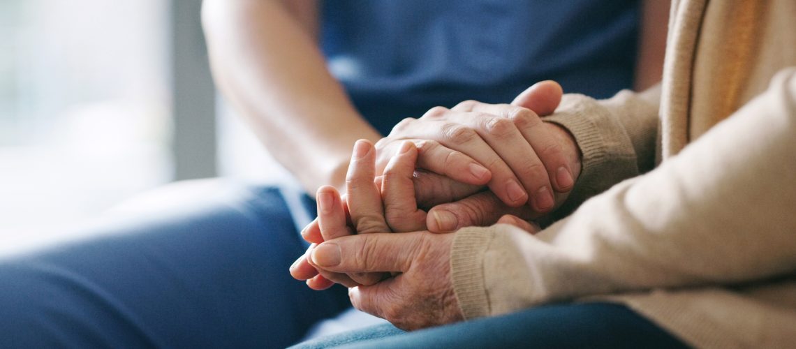 Cropped shot of a senior woman holding hands with a nurse