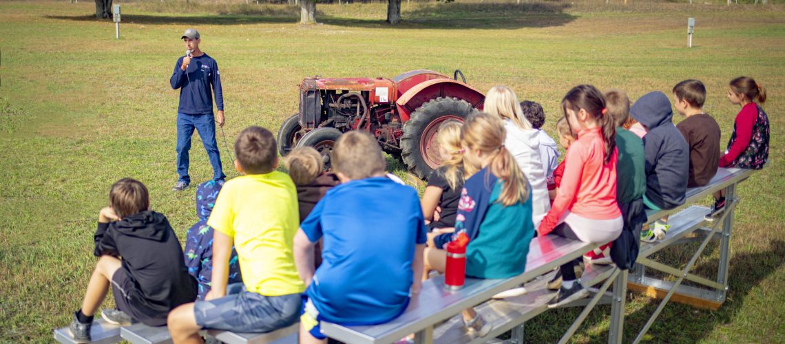 Fourth grade students sit on new bleachers purchased with the help of a $6,000 GLE People Fund Grant during the Northern Michigan Antique-Flywheelers' 2022 Student Harvest Days.