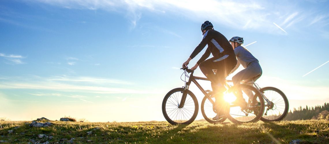 Happy mountain bike couple outdoors have fun together on a summer afternoon sunset.