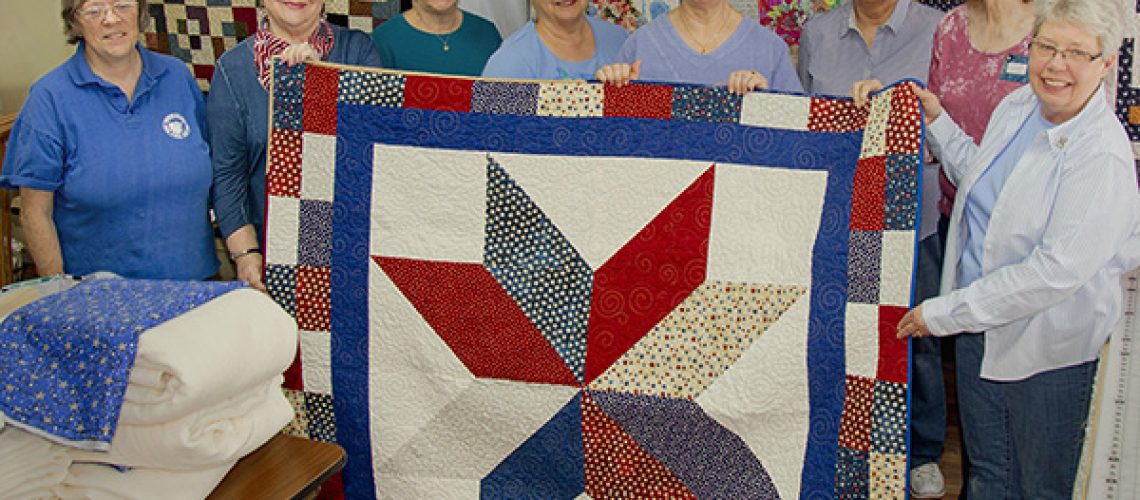 Volunteers of Little Traverse Bay Quilters Guild show Quilt of Valor made for a veteran