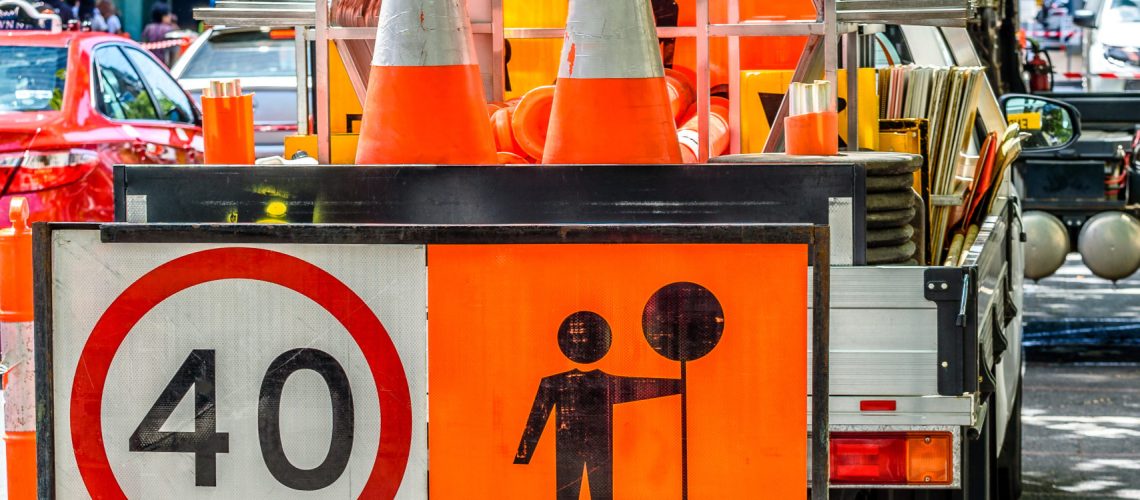 A 'Prepare To Stop' sign in front of a truck containing traffic cones and signs.