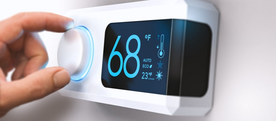 Hand turning a home thermostat knob to set temperature on energy saving mode. fahrenheit units. Composite image between a photography and a 3D background.